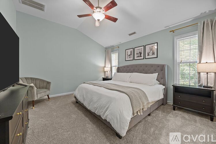 A bedroom with a bed, chair, and ceiling fan.