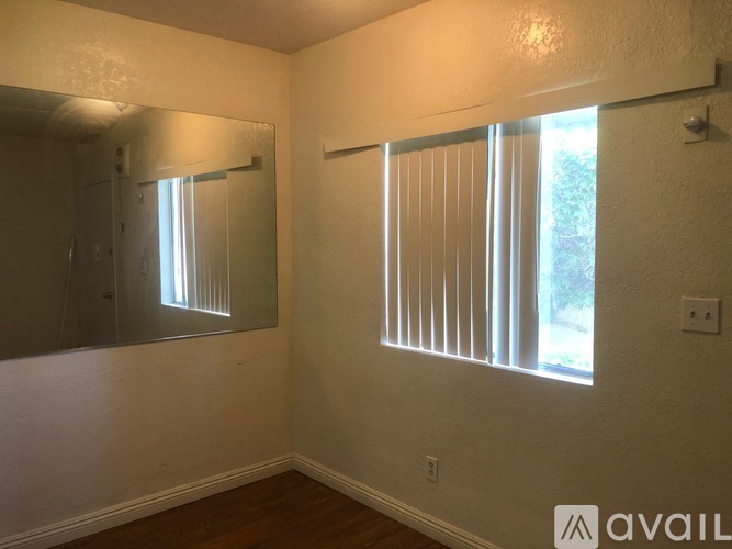 A room with a mirror and a window with blinds.
