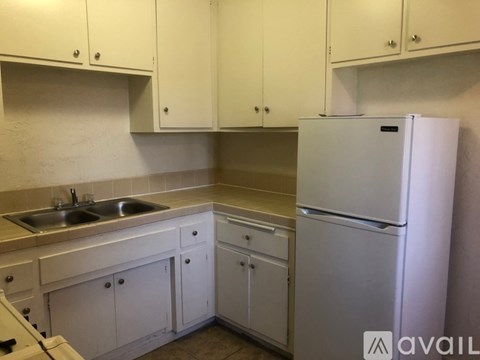 A white kitchen with a sink and a refrigerator.