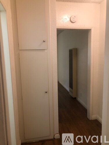 A hallway with a door on the left and a wall on the right.