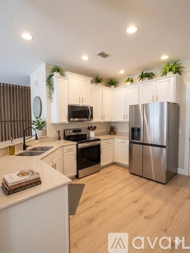 A modern kitchen with wooden floors and stainless steel appliances.