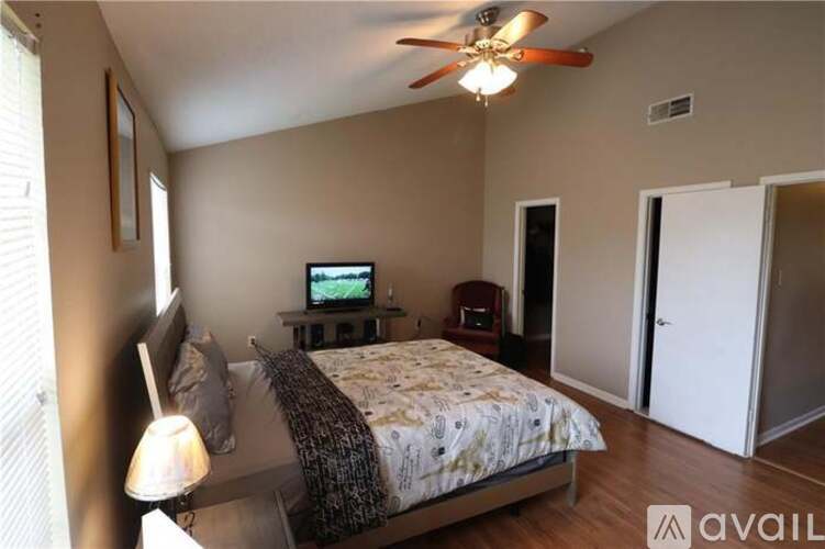 A bedroom with a bed, a television, and a ceiling fan.