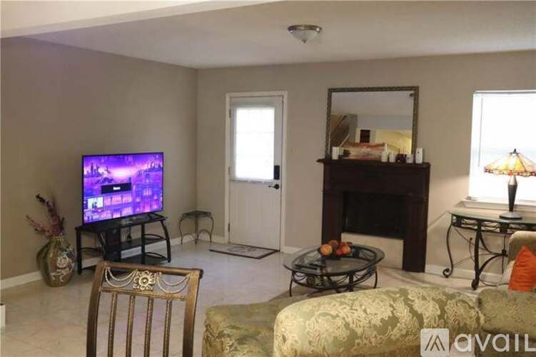 A living room with a television, a sofa, a chair, a coffee table, and a fireplace.