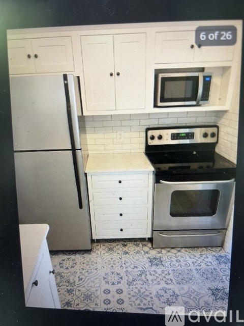 A kitchen with a refrigerator, microwave, oven and cabinets.