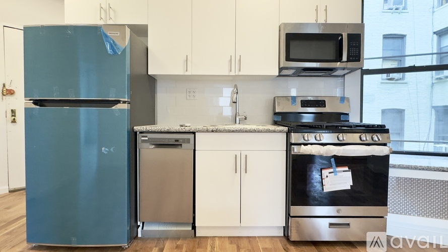 A kitchen with a blue fridge, stainless steel dishwasher, and oven.