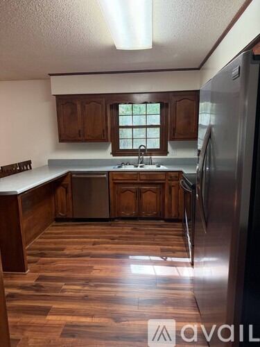 A kitchen with wooden floors and a stainless steel refrigerator.