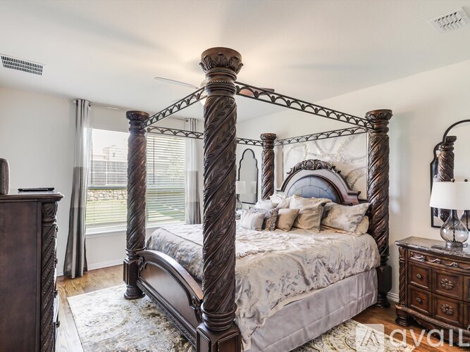 A large, ornate four poster bed in a bedroom with a white bedspread and pillows.