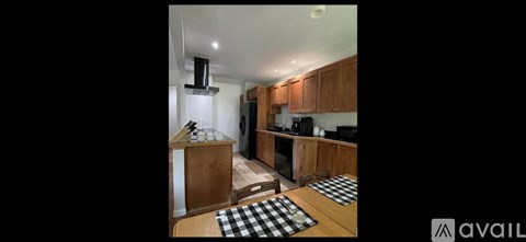 A kitchen with wooden cabinets and a black and white checkered mat on the floor.