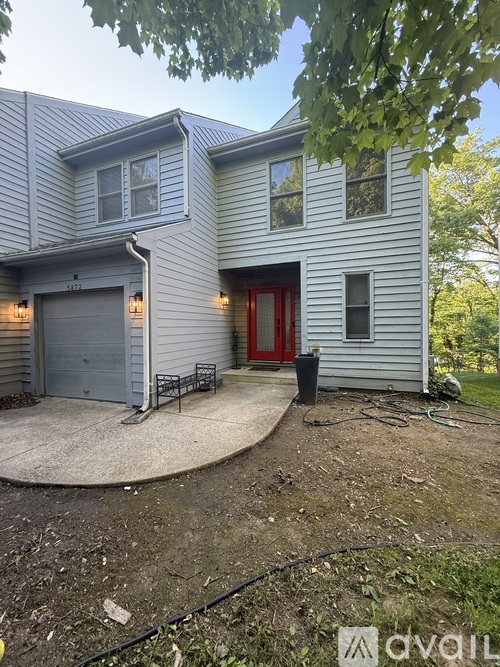 A house with a grey exterior and a red door.