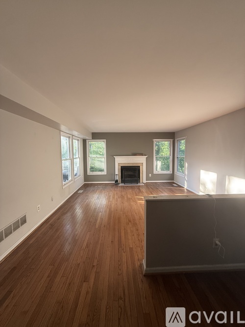 A spacious living room with wood flooring and a fireplace.