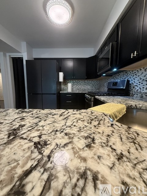 A kitchen with black cabinets and a marble countertop.