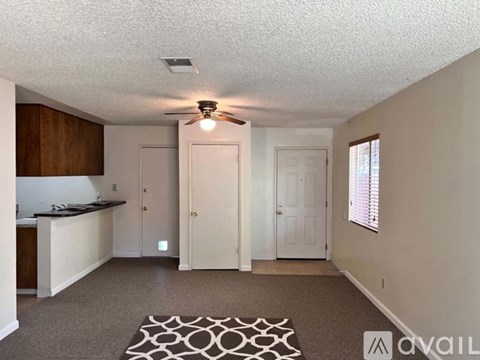 A living room with a rug on the floor and a ceiling fan above.