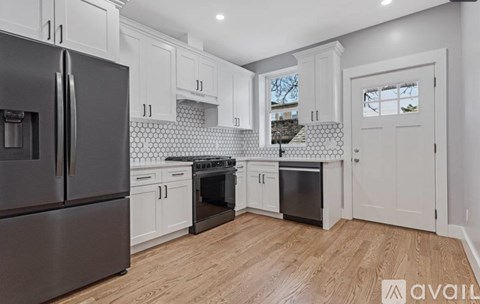 A kitchen with a black refrigerator and wooden floors.
