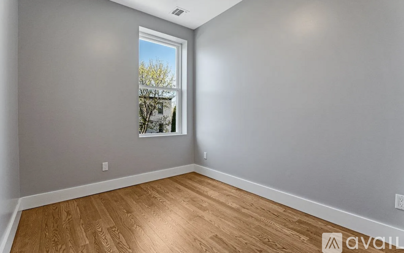 Empty room with wooden flooring and a window.