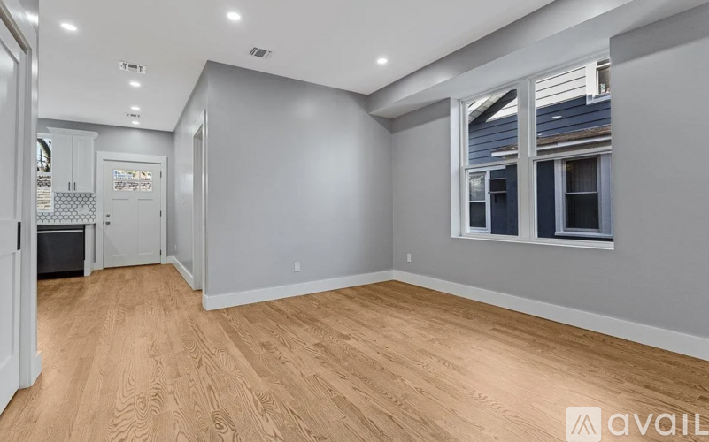 A spacious room with wooden flooring and a window with blinds.