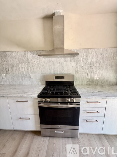 A modern kitchen with a stove top oven and white cabinets.