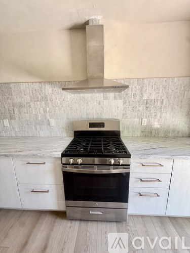 A modern kitchen with a stove top oven and white cabinets.