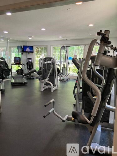 A gym with various exercise machines and a flat screen TV mounted on the wall.