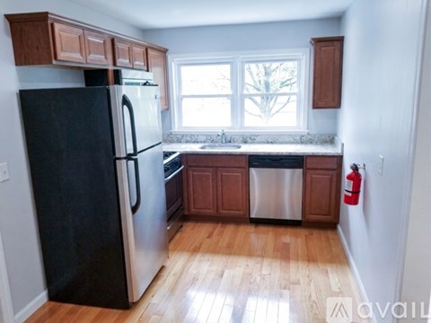 A kitchen with a black fridge and wooden cabinets.