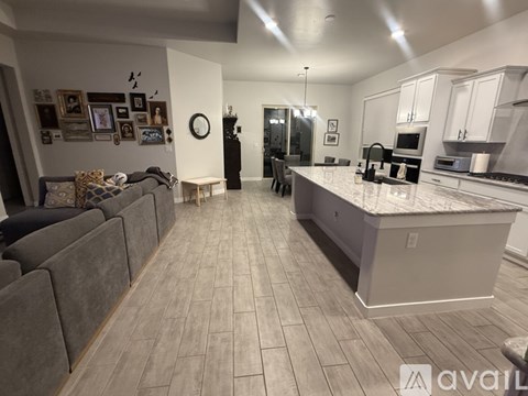 A kitchen and living room with a grey couch and a marble countertop.