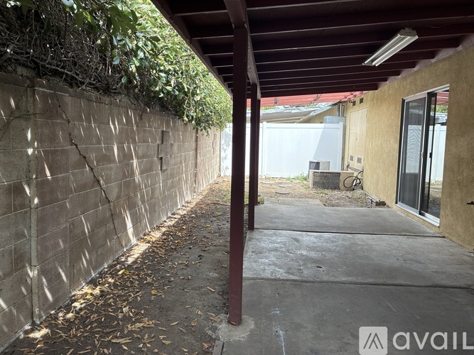 A concrete pathway leads to a building with a wall covered in greenery.