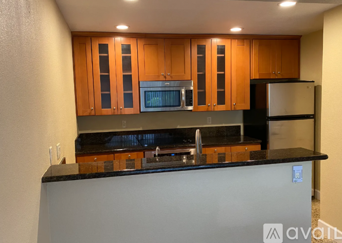 A kitchen with wooden cabinets and black countertops.