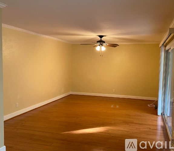 A room with a ceiling fan and wooden flooring.