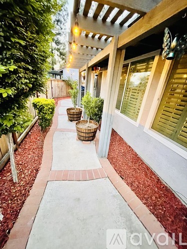 A red brick pathway leads to a building with a white roof.