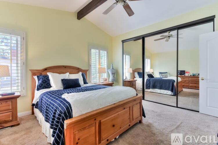 A bedroom with a large bed and a mirrored closet door.
