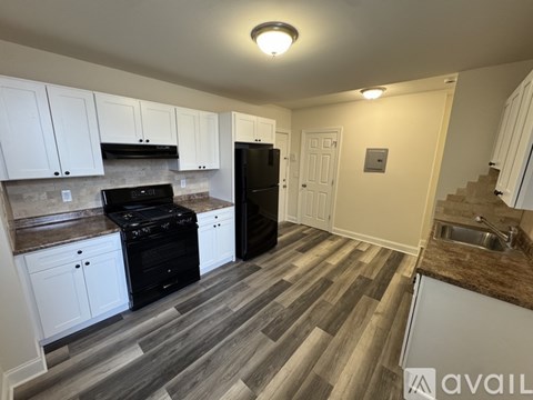 A kitchen with white cabinets and a black refrigerator.