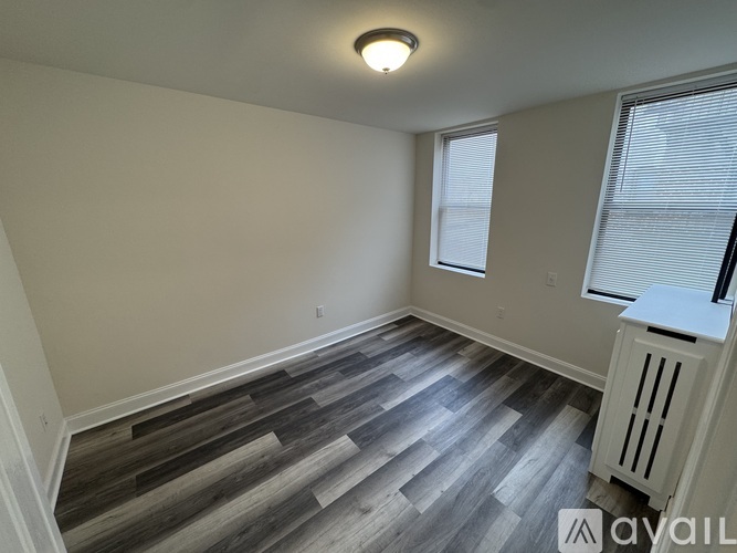 A room with wooden flooring and a window with blinds.