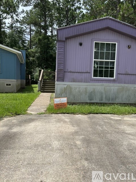 A purple building with a white window and a sign in front of it.