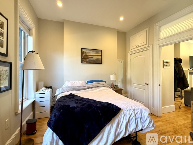 A bedroom with a large bed and a painting on the wall.