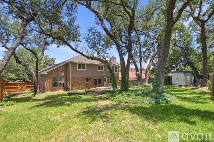 A house is surrounded by trees and grass in the foreground.