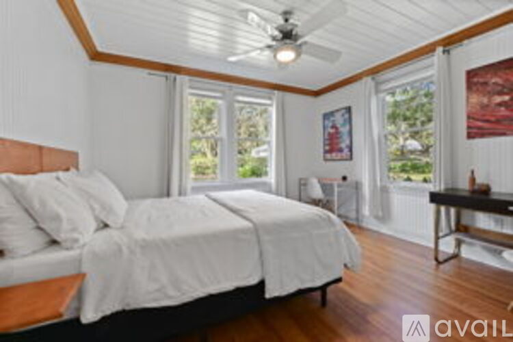 A bedroom with a large bed and a ceiling fan.