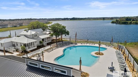 A large swimming pool is surrounded by a white fence and a house with a white roof is in the background.
