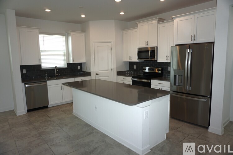 A kitchen with white cabinets and a black countertop.