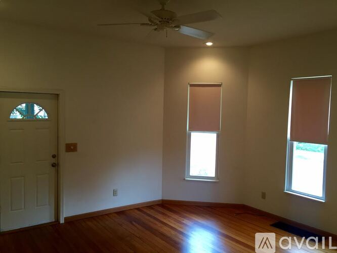 A room with a ceiling fan and two windows.