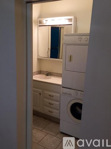A bathroom with a washing machine and a mirror.