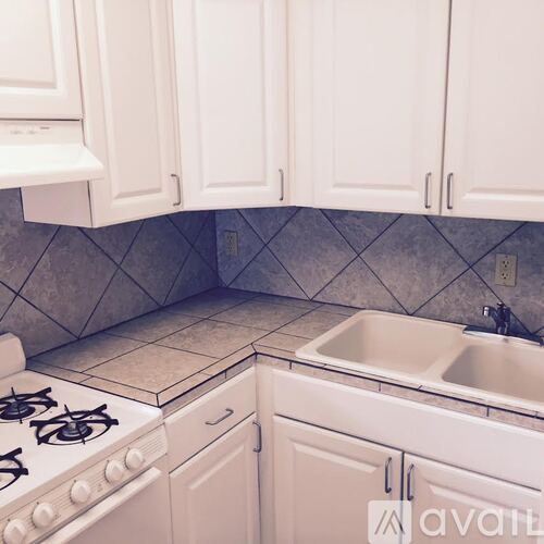 A kitchen with white cabinets and a tiled floor.