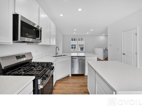 A modern kitchen with white cabinets and stainless steel appliances.
