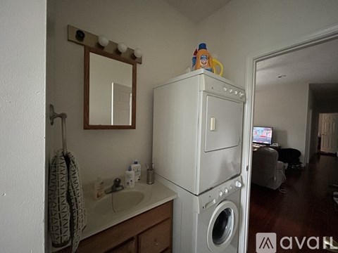 A bathroom with a washing machine on top of the cabinet.
