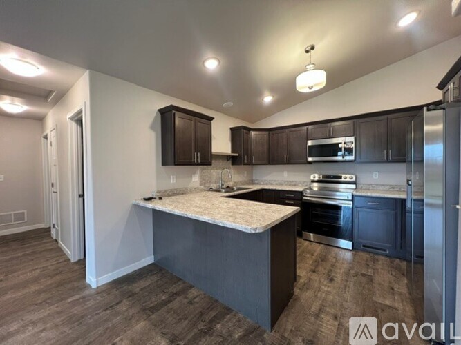 A kitchen with dark wood cabinets and a granite countertop.