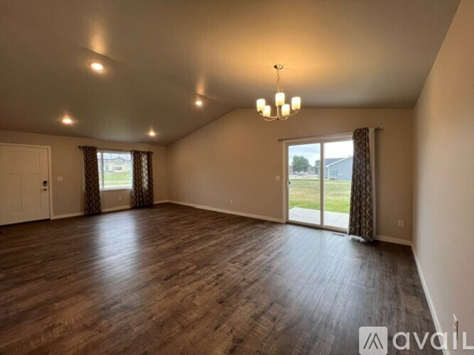 A spacious room with wooden flooring and a chandelier.