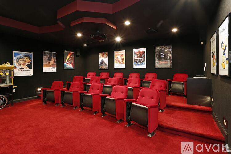 A row of red cinema seats are arranged in a dark room.