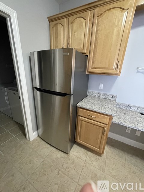 A kitchen with a stainless steel refrigerator and wooden cabinets.