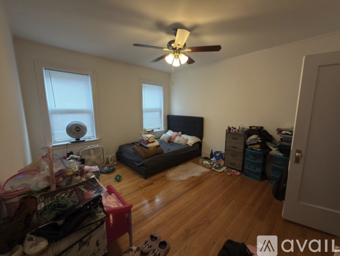 A messy bedroom with a bed, dresser, and a ceiling fan.