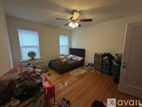 A messy bedroom with a bed, dresser, and a ceiling fan.