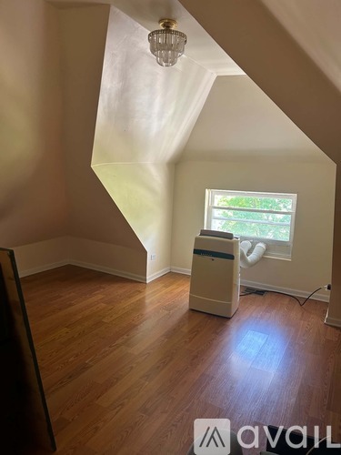 A room with wooden floors and a window with a view of trees.