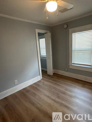 A room with wooden flooring and a window with blinds.